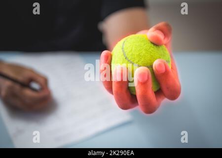 The man massages his finger by tennis balls. Office syndrome concept. Pain symptom area is shown with red color. Close up shot. Stock Photo