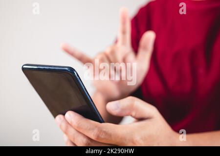 Valentine's day concept. Person uses hand to give love thru a smartphone. This shot focused on mobile. Stock Photo