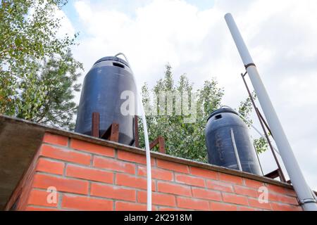 Black plastic barrels on a summer shower. Barrels for heating water from the sun. Stock Photo