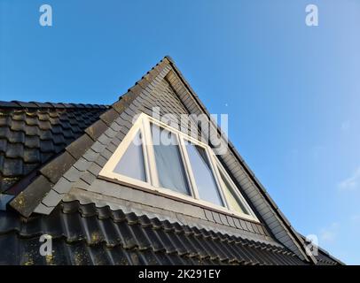 Roof window in velux style with black roof tiles. Stock Photo