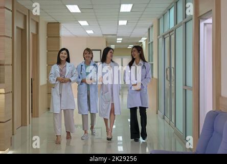 Four doctors discussing diagnosis while walking in hospital. Stock Photo