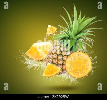 Water Splash On fresh pineapple With Leaves Isolated On Green Background Stock Photo