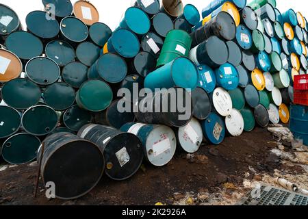 Old chemical barrels. Hazard chemical barrel with warning label. Blue, green, yellow and black oil drum. Steel oil tank. Toxic waste warehouse. Hazard waste storage in factory. Lubricant oil drum. Stock Photo