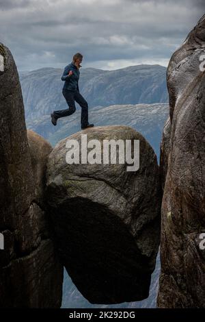 Visiting Norway Kjeragbolten located south of Lysefjorden Tourist jumps on top of the rock Stock Photo