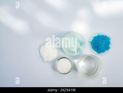 Potassium chloride and Copper(II) sulfate in chemical watch glass place next to Microcrystalline wax in glass container, alcohol in beaker and Erlenmeyer flask. Stock Photo