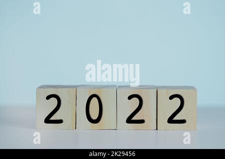 Wooden cubes with new year 2022 symbol on background and copy space.