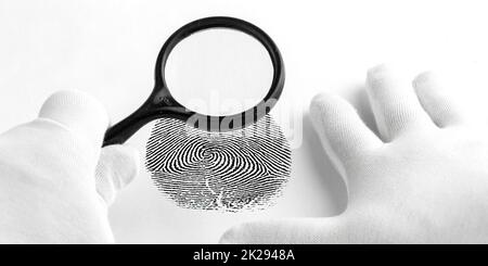 Criminology expert through a magnifying glass looking at a fingerprint. Stock Photo