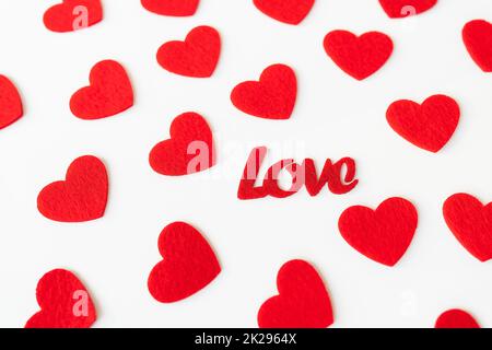 The background which consists of red hearts, the inscription love in the middle of the hearts. Love concept, greeting card for valentine's day. Stock Photo