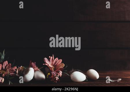 Easter holiday background. Easter eggs, flowers on wooden table. Low key Stock Photo