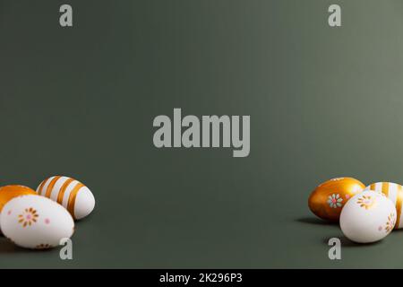 Easter holiday conceptual background. Painted golden Easter eggs on green table Stock Photo