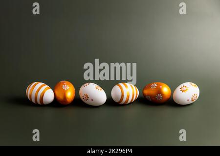 Easter holiday conceptual background. Painted golden Easter eggs on green table Stock Photo