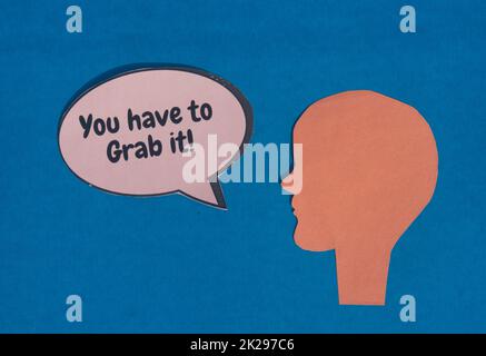 Paper human face with motivation text on speech bubble isolated on blue background. Conceptual image shows strength protest power and revolution. Stock Photo