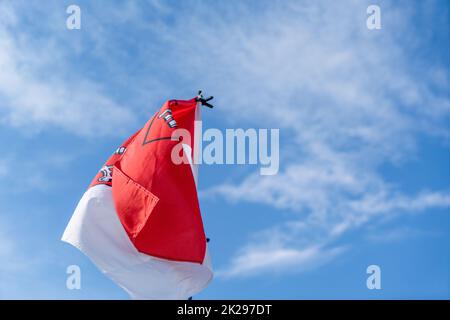 flag flies against a blue white sky on a summer day in Bavaria Stock Photo