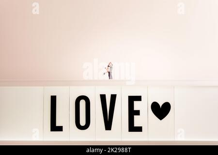 Loving couple hugging on top of a large LOVE sign Stock Photo