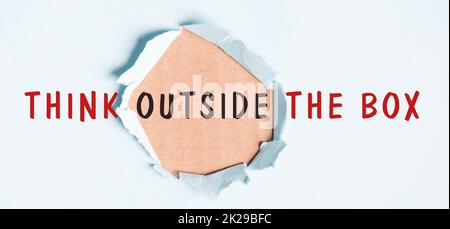 Think outside the box is standing on pieces of white paper, petrol colored background, brainstorming for new ideas, being innovative, business concept Stock Photo