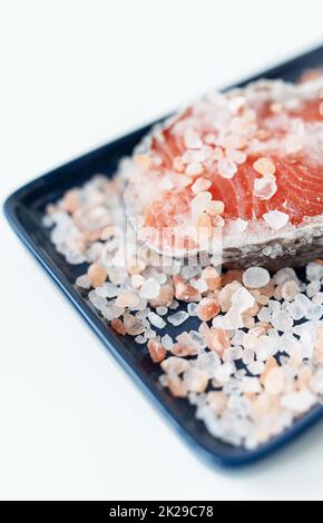 Fresh raw red salmon steak with large coarse pink salt prepared for baking on the grill lies on a blue plate. Healthy seafood food. Top view, place for an inscription. Stock Photo
