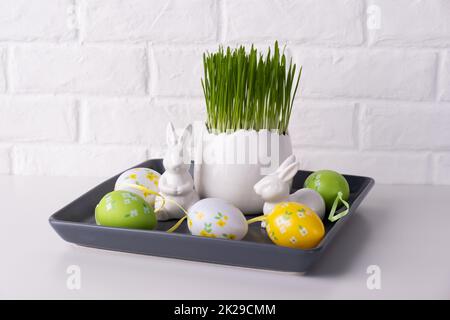 Home easter decor. Green oats, decorative rabbits and eggs Stock Photo