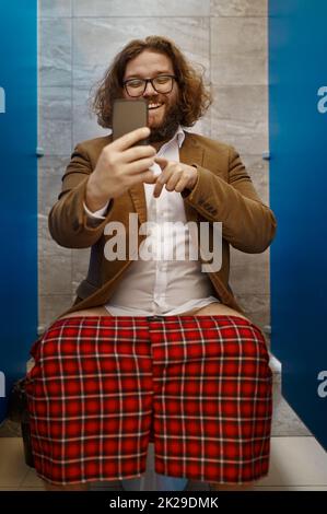 Businessman talking phone while sitting on toilet Stock Photo