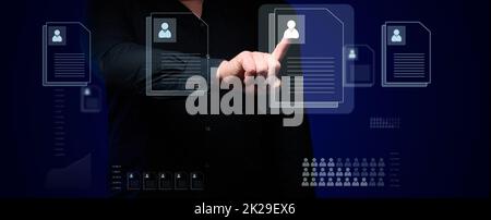 a businessman stands in front of a holographic scoreboard and selects candidates' resumes. The concept of finding employees in a company, career growth, identifying talented people Stock Photo