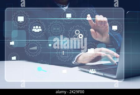 a woman sits at a table and works on a laptop and a virtual hologram with analytical icons in business. Process analysis concept, efficient management Stock Photo