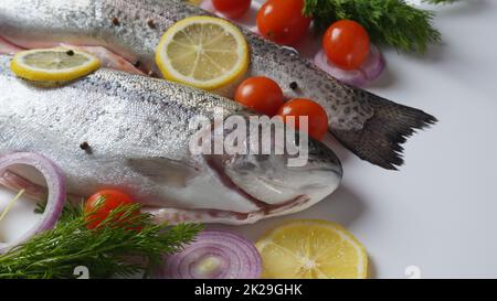 Fresh trout on a table with lemon, pepper and dill. Tasty fish ready for cooking. Healthy seafood and dieting concept. Stock Photo