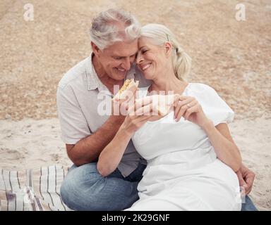 Love, picnic and elderly couple on a romantic date outdoors, celebrating retirement and freedom in a park together. Relax, food and nature with happy Stock Photo
