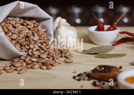 Burlap Sack of Pinto Beans on Table with Spices in Background Stock Photo