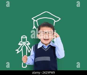 Happy child in graduation cap and holding the diploma against chalkboard. Stock Photo