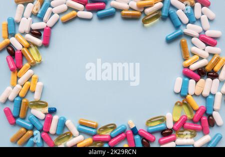 A lot of multi-colored bright tablets, in the center there is a place for an inscription. Blue background. Concepts of medicine and health. Stock Photo