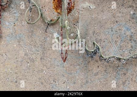Close up view on a fishing net decoration on an old weathered wall. Stock Photo