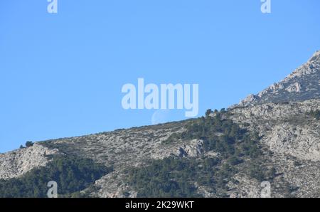 the moon, just before colliding with the mountain, Alicante province, Costa Blanca, Spain Stock Photo