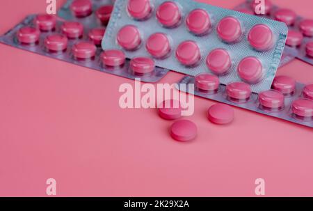 Pink tablet pills and blister pack of pills on pink background. Prescription drug. Vitamins, minerals, and supplements concept. Pharmaceutical industry. Health care and medicine. Pharmacy product. Stock Photo