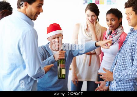 Too much of a good thing. A male employee having too much fun at the office party while his colleagues look on. Stock Photo