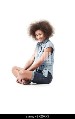 Cute and sassy. Smiling young african american woman sitting isolated on white. Stock Photo