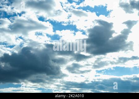 Blue sky with thunderclouds. The sun breaks through the clouds. Black clouds. Stock Photo