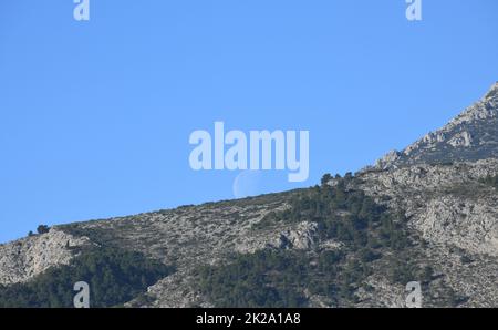 the moon, just before colliding with the mountain, Alicante province, Costa Blanca, Spain Stock Photo