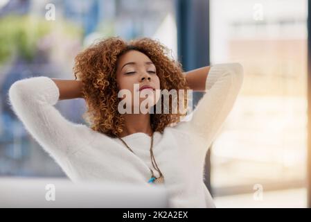 Contemplating the road to success. Shot of a young entrepreneur leaning back in her chair with her hands behind her head. Stock Photo