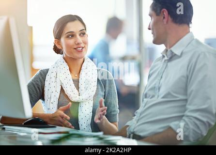 Creativity is a collaboration. Shot of designers talking together at a workstation in an office. Stock Photo