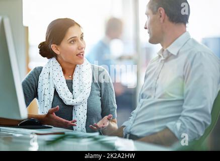 Sharing their creativity. Shot of designers talking together at a workstation in an office. Stock Photo