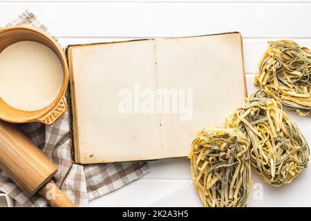 Open blank cookbook and uncooked noodles pasta. Antique recipe book Stock Photo
