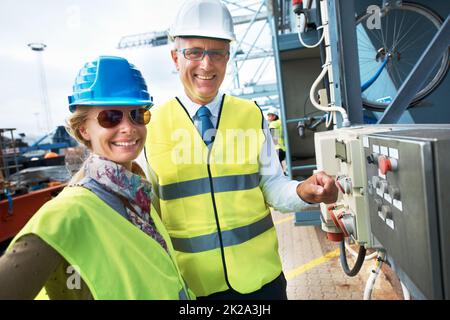 Working together leads to growth in the company. Two engineers standing near a power supply unit with broad smiles. Stock Photo