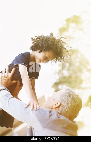 Higher grandpa, higher. A grandfather playing with his grandson in the park. Stock Photo