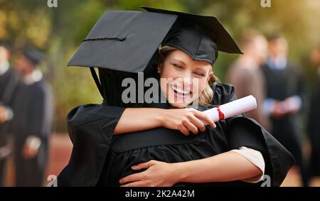 We are finally here. Two college graduates hugging one another in congratulations. Stock Photo