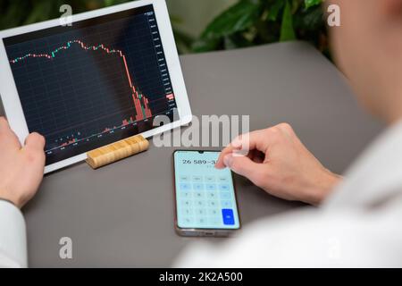 A man in a white shirt looks at an investment chart on a tablet Stock Photo