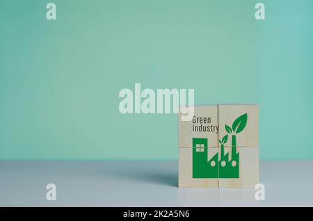 Wooden cube with industrial factory icon and green industrial font. Eco-friendly business and development concept on background. Stock Photo