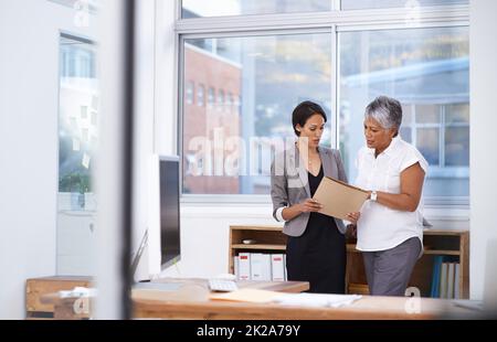 Discussing the details of their business proposal. Shot of two businesswomen discussing paperwork in the office. Stock Photo