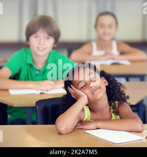 Her minds in another place entirely. A little girl daydreaming during a school lesson. Stock Photo