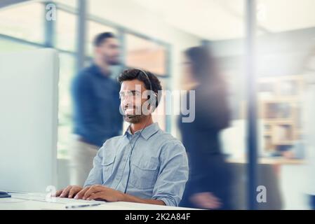 Its another busy and productive day in the office. Cropped shot of a call centre agent working in a busy office. Stock Photo