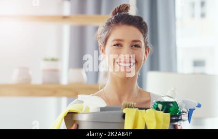 Lets clean up this mess. Closeup shot of a young woman holding a bucket with cleaning supplies at home. Stock Photo