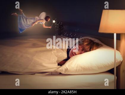 Sweet dreams, little one. Shot of a young boy sleeping peacefully while a fairy hovers above him. Stock Photo